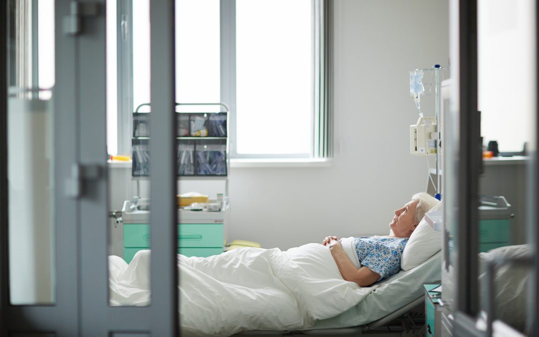 Sick aged female lying in hospital bed in ward