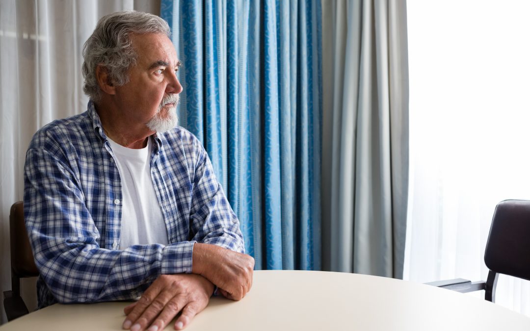 Thoughtful elderly man sitting at a table in a nursing home.